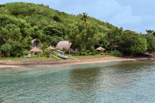 a beach with a house and a boat in the water at Gipsy Beach Bungalows in Sekotong