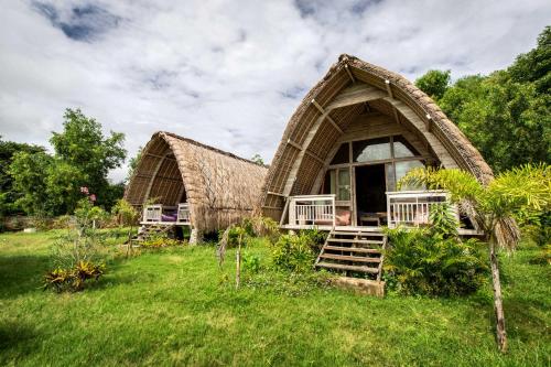 a house with a thatched roof in a field at Gipsy Beach Bungalows in Sekotong