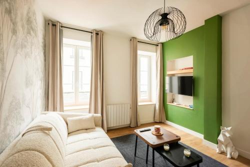 a living room with a white couch and a green wall at Le Goupil in Chalon-sur-Saône