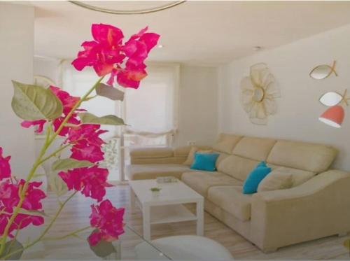 een woonkamer met een bank en roze bloemen bij Alojamiento Oasis Playa in Águilas