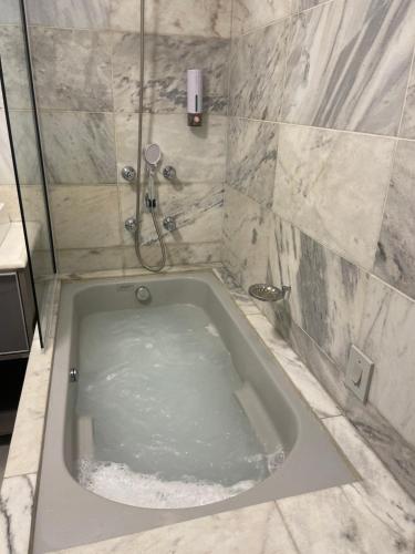 a bath tub in a bathroom with a shower at Batel Guest House-Suite Queen Quarto 1 in Curitiba