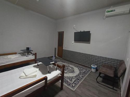 a room with two beds and a tv on the wall at Caravan Hostel in Tashkent International Airport