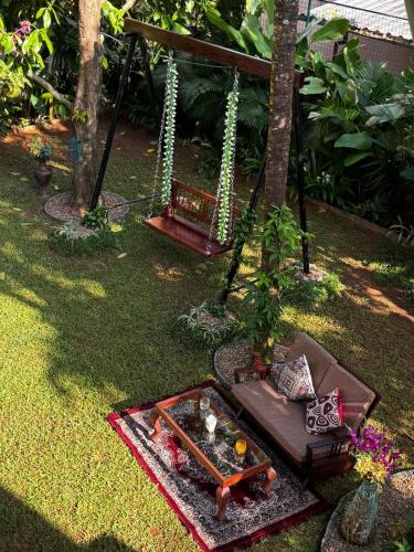 a swing in a garden with a table and pillows at Scarlet's Cottage & Tea Garden in Cochin