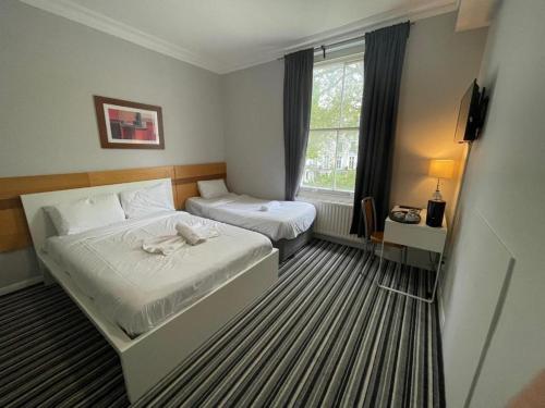 Una habitación de hotel con dos camas y una ventana. en Princes Palace, en Londres