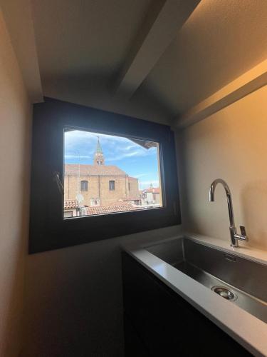 a kitchen with a sink and a window with a building at Can Los arcos in Chioggia