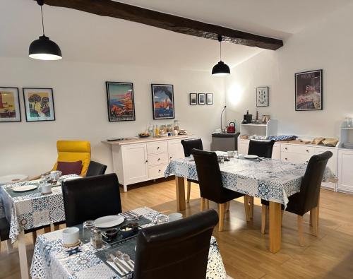 a dining room with tables and chairs and a kitchen at Les Deux Chevaux Chambres d’Hôtes in Rouvenac