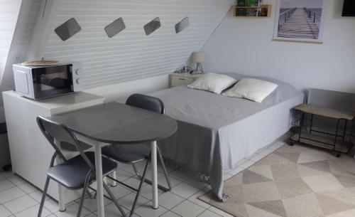 a small bedroom with a small table and a bed at Le studio du dolmen à Plouharnel in Plouharnel