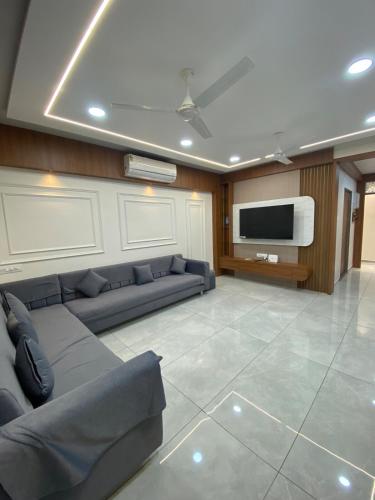 Una sala de estar con un sofá y un televisor de pantalla plana. en Home away from Home close to Swaminarayan Temple, en Nadiād