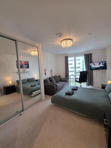 a bedroom with a bed and a couch and a mirror at 3 Bedroom apartment from F&A properties in North Woolwich