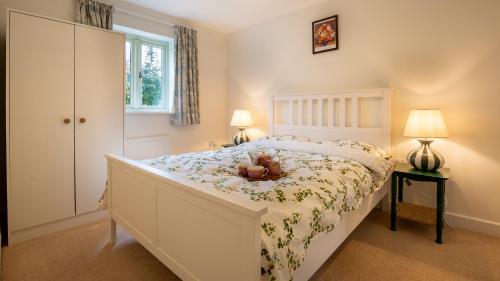 ein Schlafzimmer mit einem Bett, auf dem ein Teddybär liegt in der Unterkunft Wildflowers Cottage in Bourton on the Water