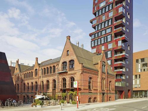a large brick building next to a tall building at 25hours Hotel Altes Hafenamt in Hamburg