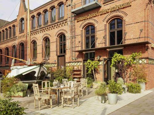 a brick building with tables and chairs in front of it at 25hours Hotel Altes Hafenamt in Hamburg