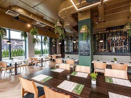 a restaurant with tables and chairs and wine bottles at Mercure Bialystok in Białystok