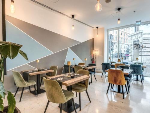a restaurant with tables and chairs and a large window at Mercure Roma Centro Termini in Rome