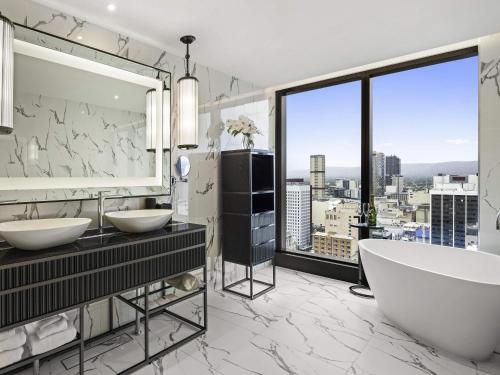 a bathroom with two sinks and a large window at Sofitel Adelaide in Adelaide