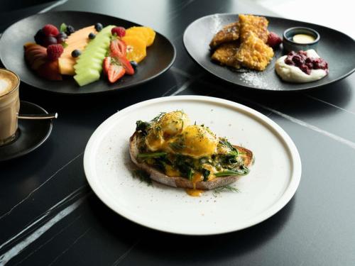 Una mesa con platos de comida sobre platos con fruta. en Sofitel Adelaide, en Adelaida