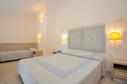 a bedroom with a large white bed with blue accents at Cala Fiorita in Agrustos