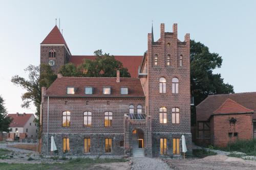 ein altes Backsteingebäude mit einem Uhrturm in der Unterkunft Verwalterinnenhaus in Werben