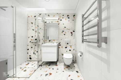 a white bathroom with a toilet and a shower at Bright 2BR with Private EV Parking, workspace, AC in Kaunas