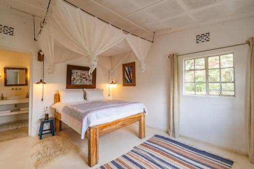 a bedroom with a bed and a window at Sanctuary Farm House 5-bedroom Lodge In Wildlife in Naivasha