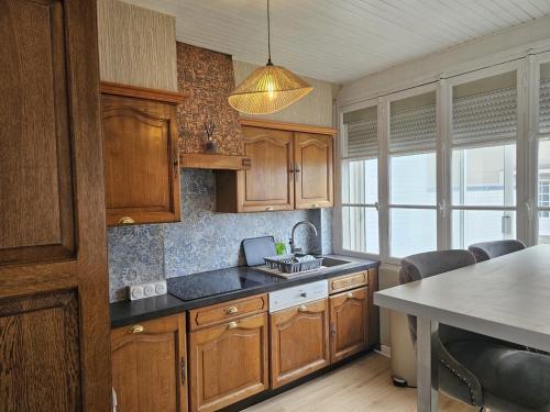 a kitchen with wooden cabinets and a sink at Appartement lumineux 50M2 proche mer-centre Portel in Le Portel