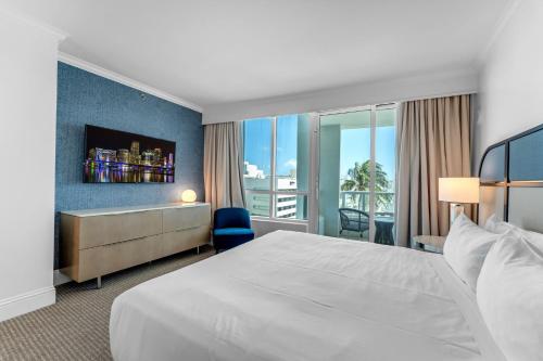 a hotel room with a large bed and a window at Fontaine Bleau Suite - Street & Partial Ocean view in Miami Beach