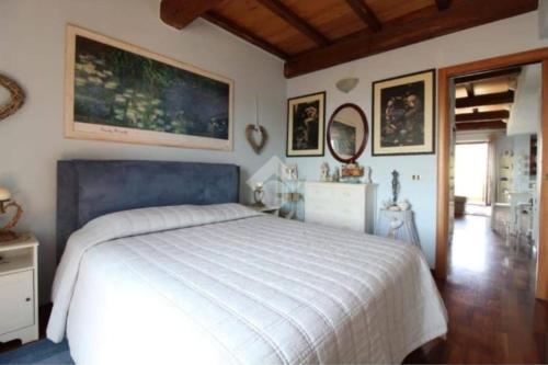 Un dormitorio con una cama blanca y algunas fotos en la pared en Appartamento La Dimora Del Lupo, en Morlupo