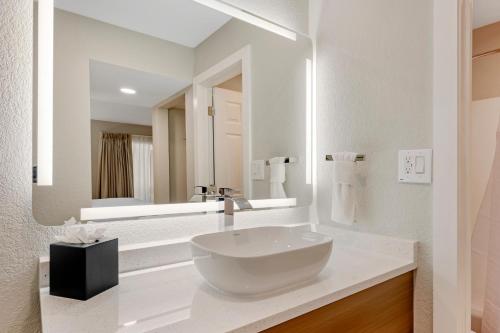 a bathroom with a large white bowl sink in front of a mirror at MainStay Suites Springfield South - Battlefield Rd in Springfield