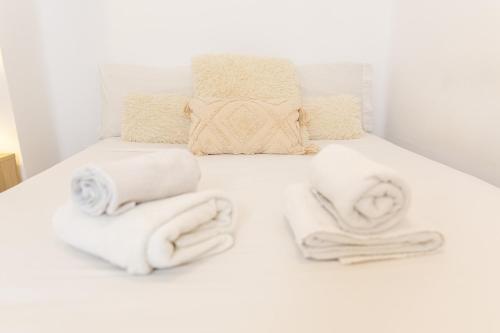 a white bed with towels on it at Canasteros Apartments ! in Málaga
