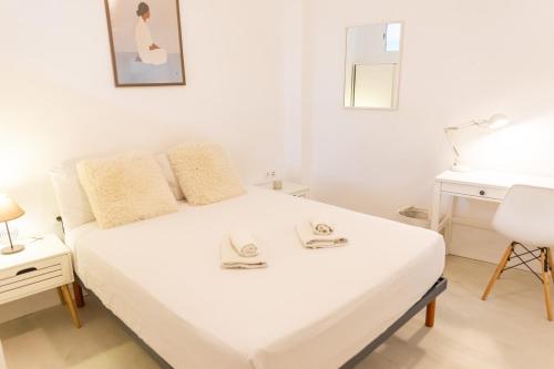 a white bedroom with a bed and a desk at Canasteros Apartments ! in Málaga