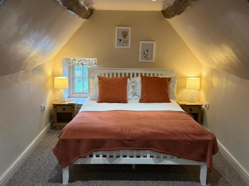 a bedroom with a bed with orange pillows and two lamps at Tuckers Grave Inn - Historic Inn & Cider Pub in Norton Saint Philip