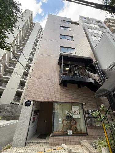 a tall building with a window and a balcony at Wabi Sabi Hostel Shinjuku West in Tokyo
