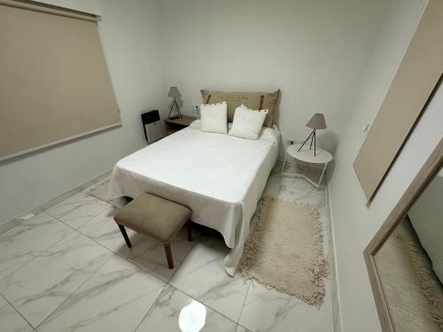 een witte slaapkamer met een bed en een stoel bij COMPLEJO JONAS SALK - departamento de 1 dormitorio amoblado in San Francisco