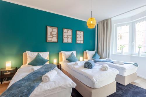 two beds in a room with a blue wall at Aparties I Bielefeld mitte I voll ausgestattet I hochwertige Betten I Top Lage in Bielefeld