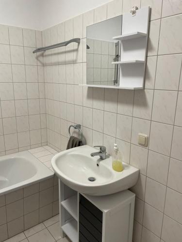 a white bathroom with a sink and a mirror at Gemütliche 2-Zimmerwohnung in Schönefeld