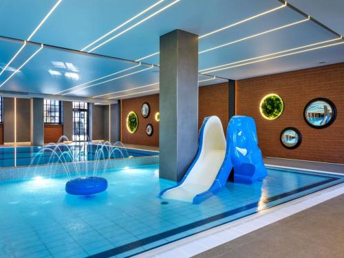 a pool with a slide and a water park at Mercure Krakow Fabryczna City in Kraków