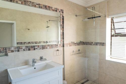 een badkamer met wastafel en douche met spiegel bij Begonias Eden in Helderberg College