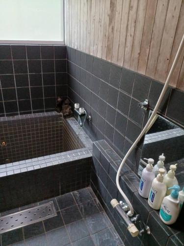 a bathroom with a black tiled shower with milk bottles at グランメール in Myoko