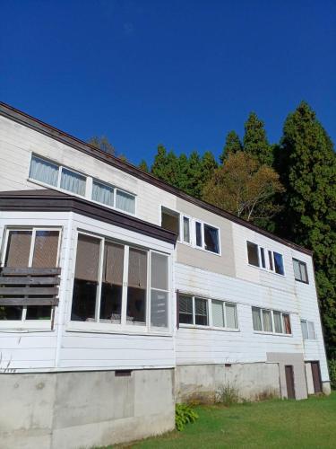 a white building with windows and trees in the background at グランメール in Myoko
