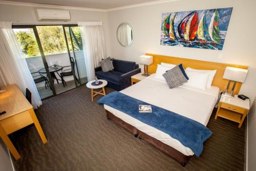 ブリスベンにあるManly Marina Cove Motelの大きなベッドと椅子が備わるホテルルームです。
