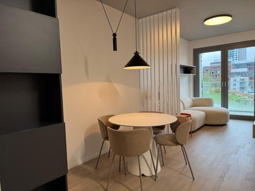 a living room with a table and chairs and a couch at Metropolis- brand new apartment with free parking in Nivy