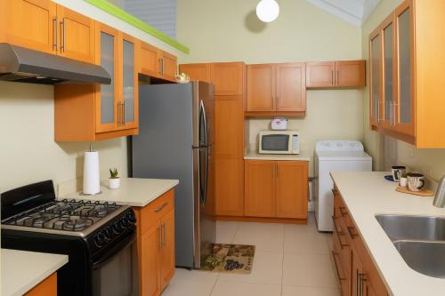Una cocina con gabinetes de madera y un refrigerador de acero inoxidable. en Tropical Escape in Richmond with Pool & Gym Perfect Paradise Getaway Sleeps 7 Perfect for Families, en Richmond