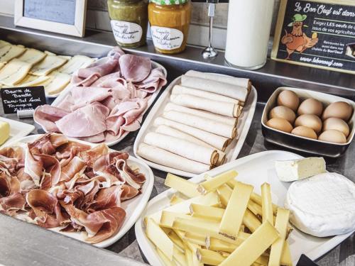 Un mostrador con diferentes tipos de carnes y quesos. en Mercure Belfort Centre, en Belfort