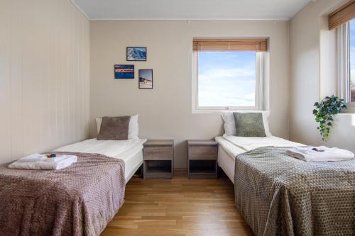 two beds in a room with a window at Fjellheim Kurs- og Misjonssenter in Tromsø