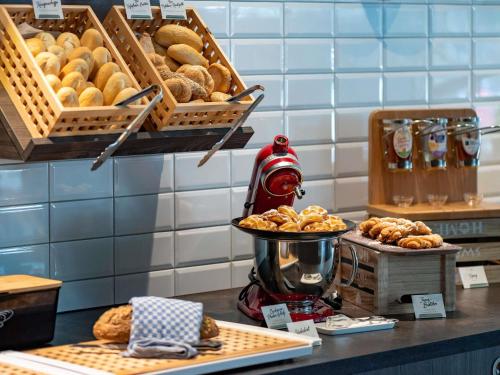 Un mostrador de panadería con cestas de pan y pasteles en ibis Styles Hamburg Barmbek, en Hamburgo