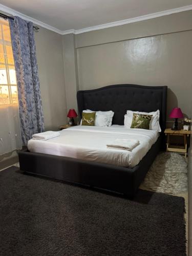 a bedroom with a large bed with a black headboard at Lovely 2-bedroom Fully-Furnished apartment in Nanyuki
