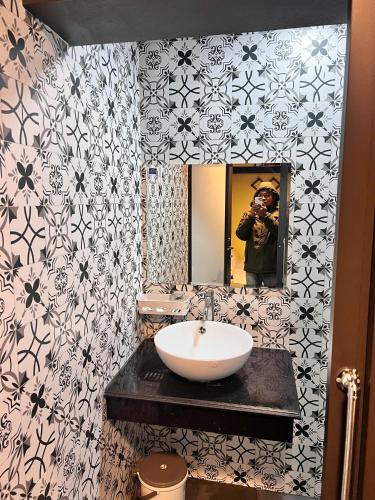 a man taking a picture of a sink in a bathroom at Hầu Thào Villa & Coffee in Sapa