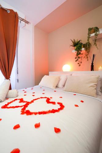 a bed with red rose petals on it at Suite romantique avec Spa in Le Mans