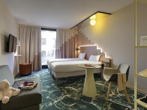 a hotel room with a bed and a couch at ibis Styles Zurich City Center in Zurich