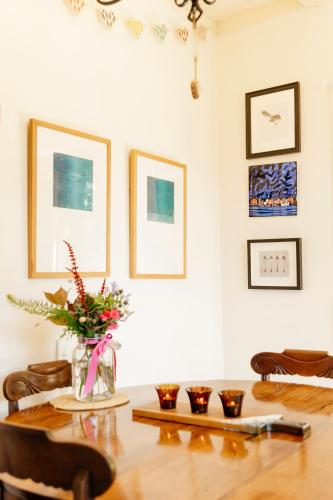 a dining room with a table with a vase of flowers at amelie, urban retreat awaits in Nelson